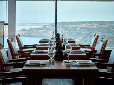 Elegantní restaurace s výhledem na pobřeží, prostřené stoly se židlemi u okna.