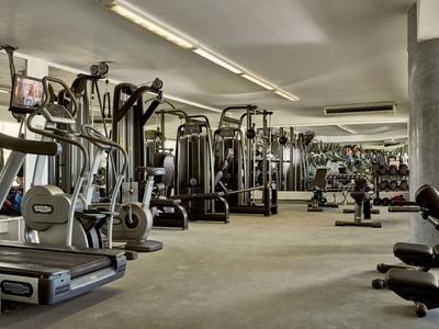Fitnessraum im Hotel mit modernen Geräten und großen Spiegeln an den Wänden.