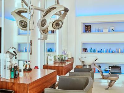 Moderner Friseursalon mit Holzarbeitsflächen, grauen Stühlen und blauer LED-Beleuchtung.