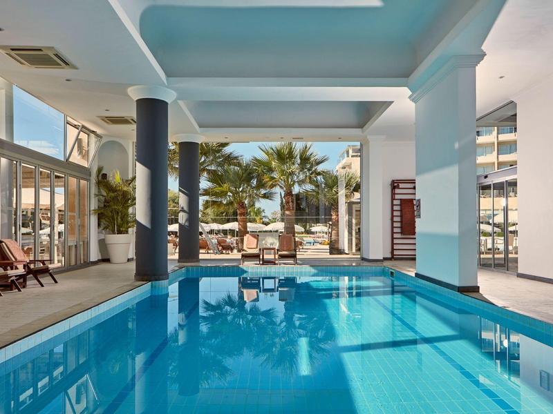 Moderner Innenpool mit Palmenblick und Sonnenliegen in einem Hotel