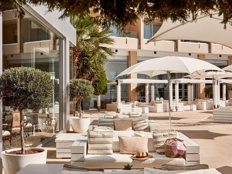 Luxuriöser Außenbereich eines Hotels mit weißen Sonnenliegen und großen Sonnenschirmen.