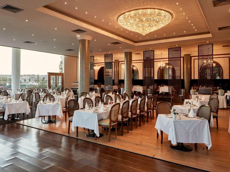 Elegantes Restaurant mit gedeckten Tischen und Kronleuchtern in einem Hotel.