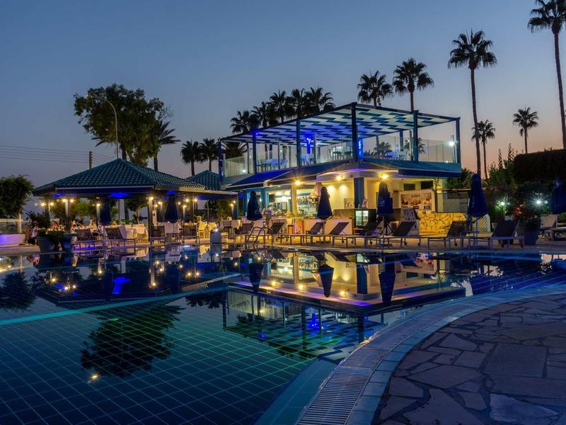 Luxuriöser Poolbereich mit Beleuchtung, Palmen und Sitzplätzen im Dämmerlicht.