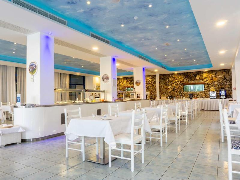 Helles Restaurant mit weißen Tischen, Stühlen und einer blauen Decke mit Sterneneffekt.