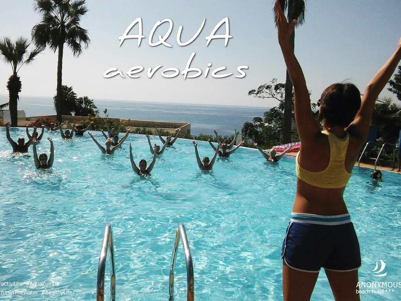 Menschen machen Aqua-Aerobic im Pool mit Blick aufs Meer und Palmen im Hintergrund.