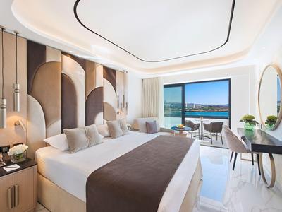 Chambre d'hôtel moderne avec lit double, vue sur la mer et intérieur lumineux et élégant.