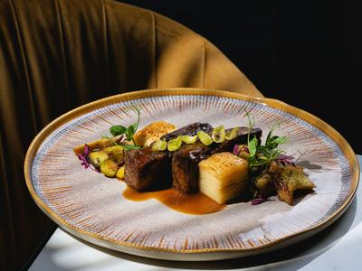 Plat élégant et soigneusement dressé sur une assiette blanche devant un fond marron.