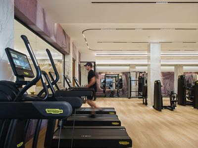 Salle de sport moderne avec tapis roulants et équipements d'entraînement dans un hôtel.