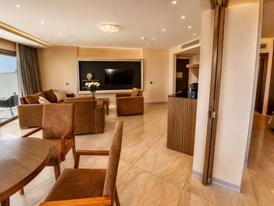 Chambre d'hôtel moderne avec coin salon, grand téléviseur et accès au balcon.