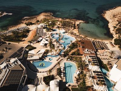 Vue aérienne d'un complexe avec plusieurs piscines, bâtiments et une côte en bord de mer.