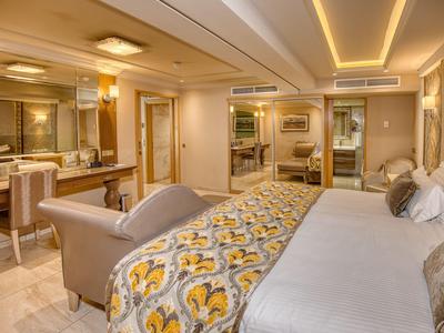 Chambre d'hôtel luxueuse avec grand lit, banc confortable et espace bureau élégant.