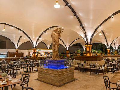 Grand restaurant extérieur couvert avec fontaine centrale et éclairage moderne.