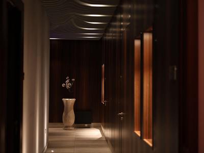 Un couloir étroit et faiblement éclairé avec des murs sombres et un vase au bout.