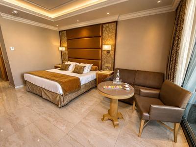 Chambre d'hôtel moderne avec lit double, coin salon et grande fenêtre.