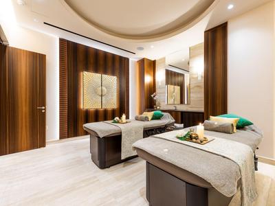 Salle de bien-être moderne avec deux tables de massage et accents en bois chaleureux.