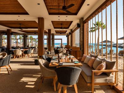 Espace extérieur confortable d'un hôtel avec mobilier en bois et vue sur la mer à la plage.