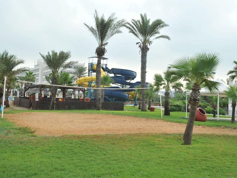 Grüner Garten mit Palmen und Wasserrutschen in einem Hotelresort.
