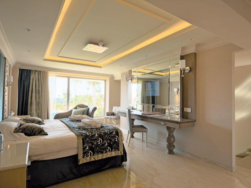 Helles, modernes Hotelzimmer mit großem Bett, Sitzbereich und dekorativem Beleuchtungselement.