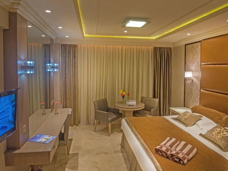 Modern eingerichtetes Hotelzimmer mit großem Bett, Fernseher und Sitzbereich.