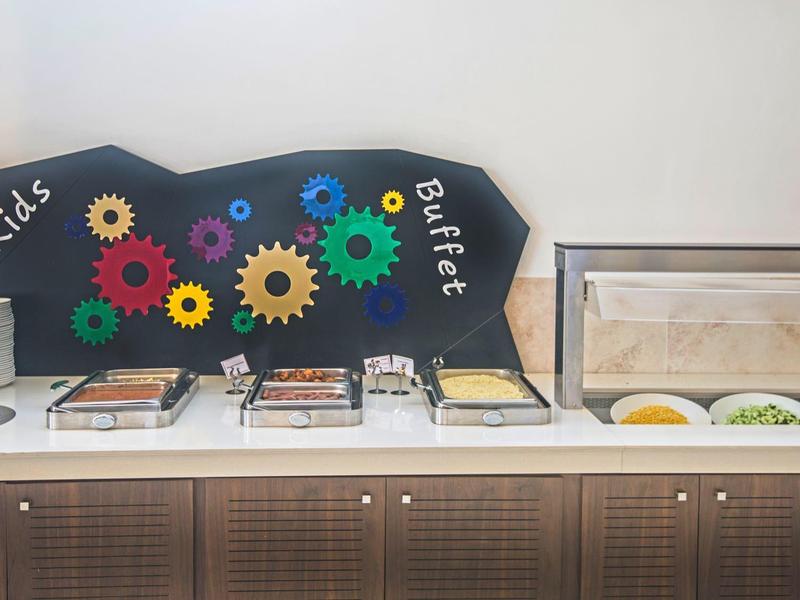 Buffet mit verschiedenen Speisen und dekorativer Tafel mit bunten Zahnrädern.