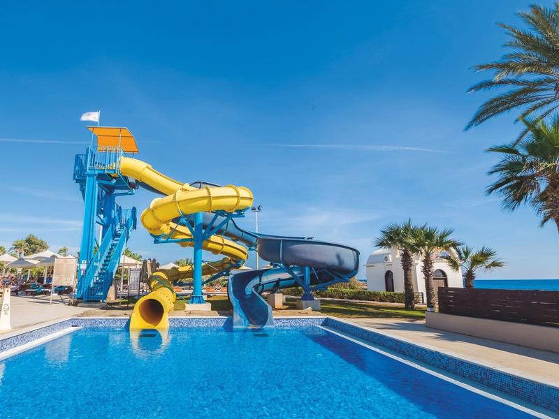 Wasserpark mit großen, bunten Wasserrutschen und Pool unter blauem Himmel.