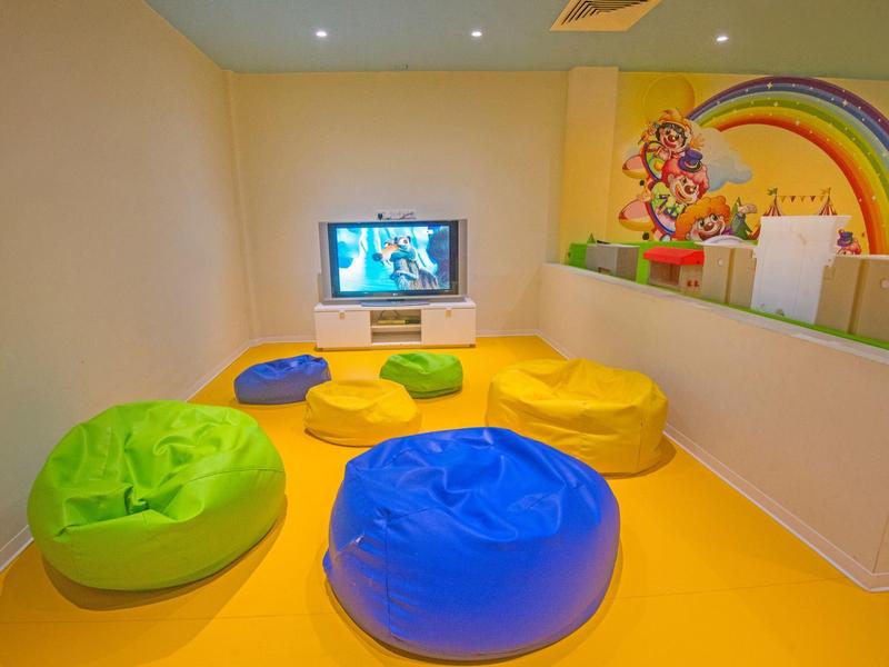 Kinderspielecke mit bunten Sitzsäcken, Fernseher und Regenbogenwandgestaltung.