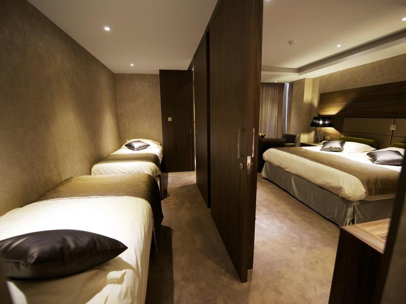 Zimmer mit zwei Einzelbetten links und einem Doppelbett rechts, durch Schiebetür getrennt.