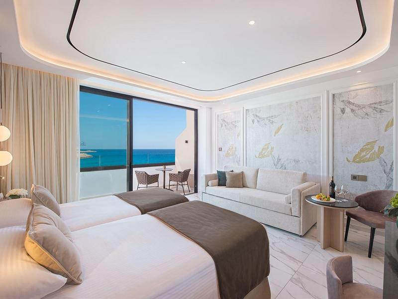 Elegantes Hotelzimmer mit Meerblick, Doppelbett, Sofa und Balkon.