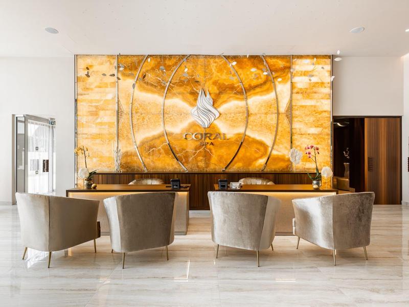 Moderner Hotel-Loungebereich mit bequemen Sesseln und dekorativer honigfarbener Wandgestaltung.