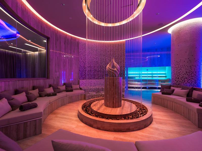 Modernes Spa mit runder Lounge, weicher Beleuchtung und eleganter Skulptur im Zentrum.