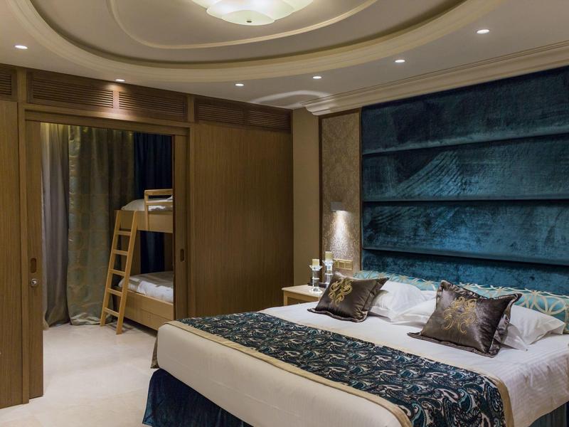 Modernes Schlafzimmer mit Doppelbett und Sicht auf ein zweites Zimmer mit Etagenbett.