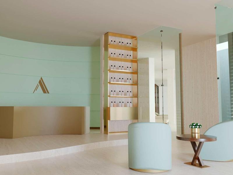 Moderner Wartebereich mit hellgrünem Sofa, kleinem Holztisch und Empfangstheke in hellem Raum.