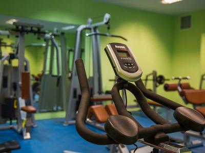 Fitnessraum mit Trainingsgeräten und grünen Wänden in einem Hotel