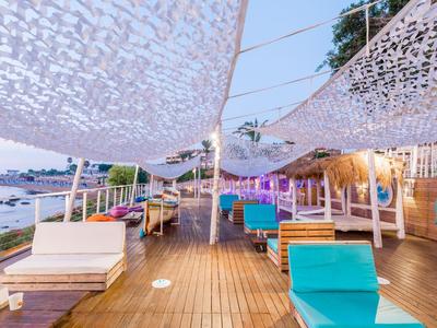 Area lounge aperta con sedute colorate e vele bianche vicino a un lungomare