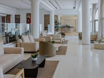 Hall d'hôtel lumineux avec canapés confortables, fauteuils et grandes fenêtres