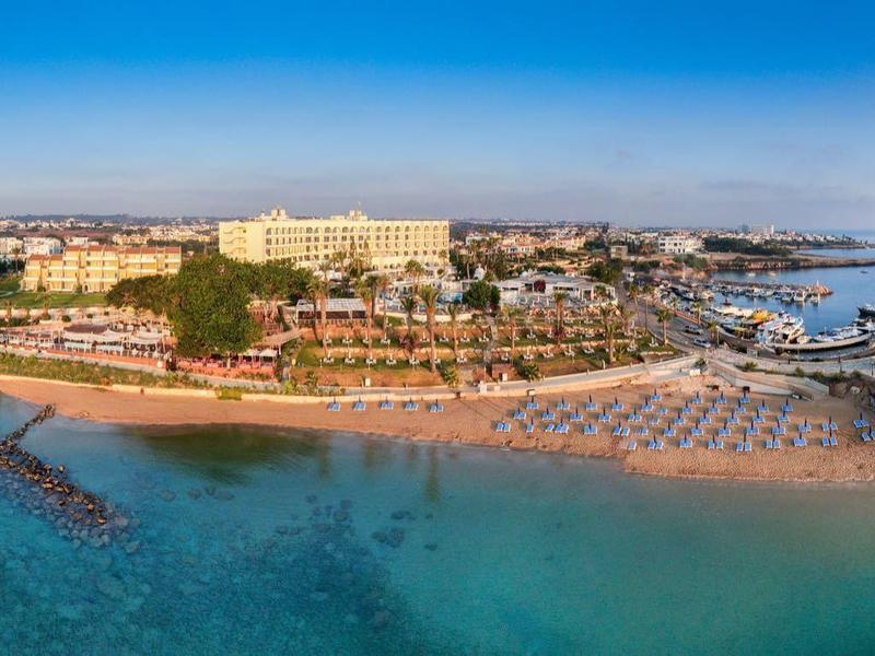 Vue panoramique d'une plage avec parasols et une ville côtière pittoresque par temps clair.