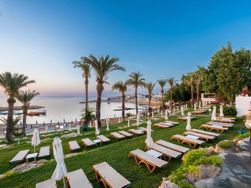 Hôtel en bord de mer avec chaises longues et palmiers au coucher du soleil