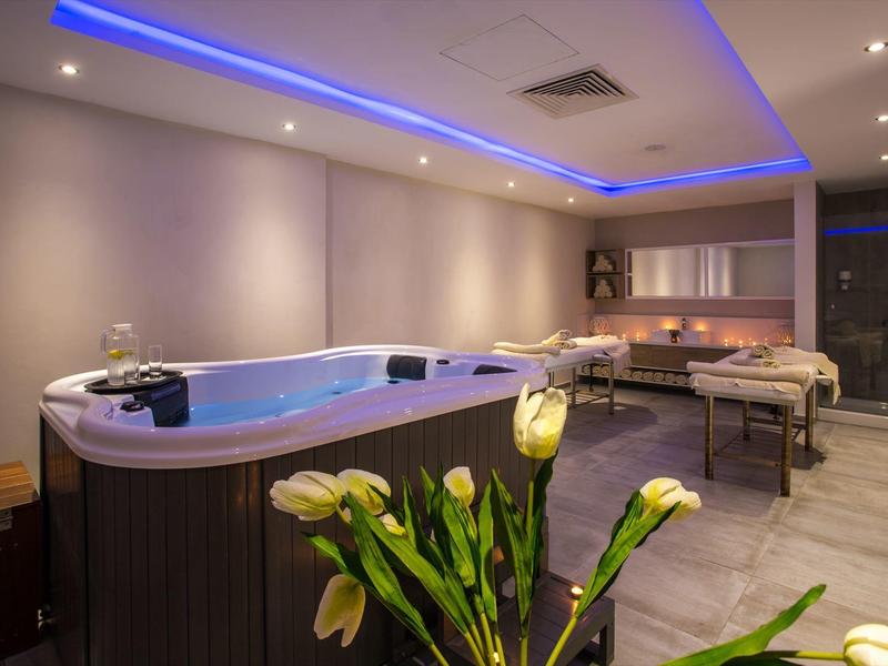 Espace bien-être moderne avec jacuzzi, table de massage et éclairage d'ambiance.
