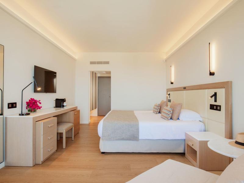 Chambre d'hôtel moderne avec lit double, bureau, télévision et sol en bois chaleureux.