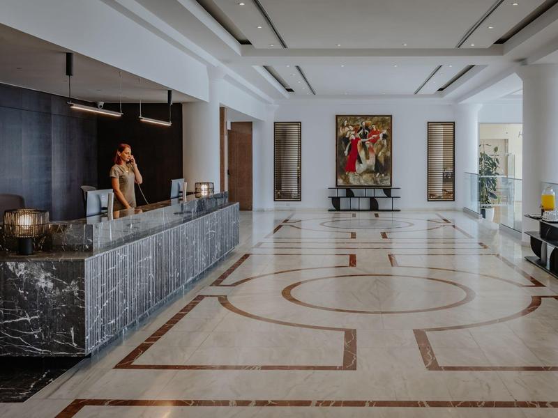 Hall d'hôtel spacieux avec sol en marbre élégant et un long comptoir d'accueil à gauche.