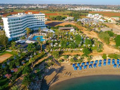 Vue sur un grand hôtel avec piscine, plage et parasols au bord de la mer.