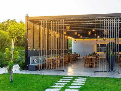 Terrasse extérieure moderne avec tables et chaises sous un toit ouvert.