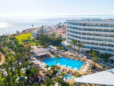 Modernes Hotel mit großem Pool, Palmen und Blick aufs Meer bei sonnigem Wetter