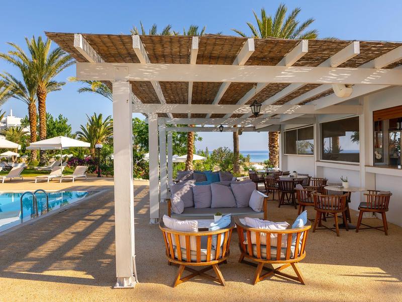 Salon confortable avec sièges à côté de la piscine dans un hôtel avec palmiers.