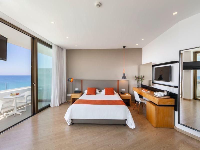 Chambre d'hôtel moderne avec lit double, vue sur la mer et accès au balcon