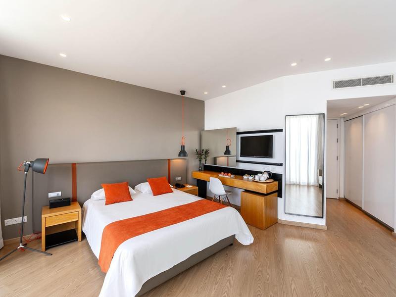 Chambre d'hôtel moderne avec lit double, bureau, TV et sol en bois