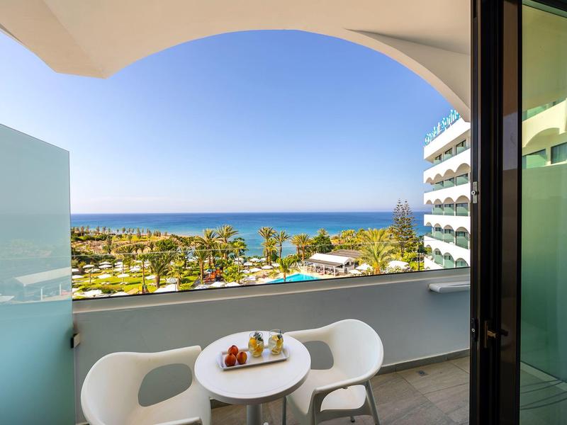 Balcon avec table moderne et chaises offrant une vue sur la mer par temps ensoleillé.