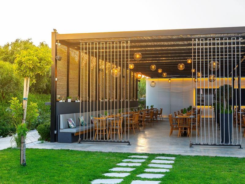 Terrasse extérieure moderne avec tables et chaises sous un toit ouvert.