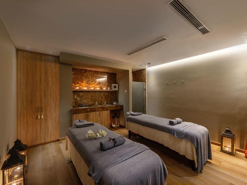 Espace de massage confortable avec deux tables de traitement et éclairage tamisé.