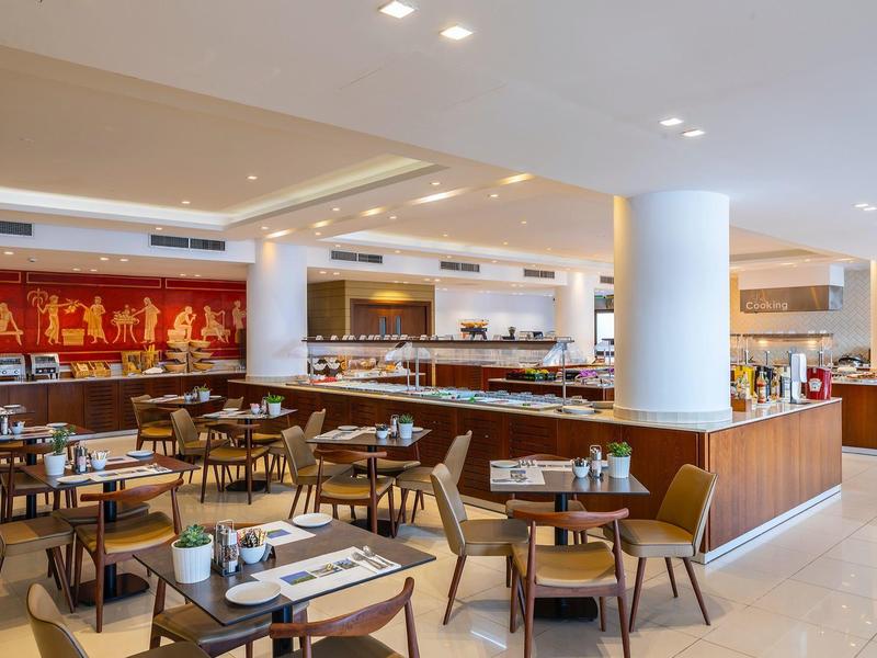 Restaurant d'hôtel moderne avec mobilier en bois et buffet ouvert.